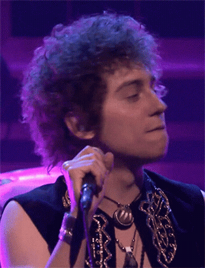 Man With Curly Hair Singing Into Microphone Purple Background GIF