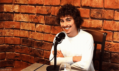Man With Curly Hair Smiling At Microphone GIF