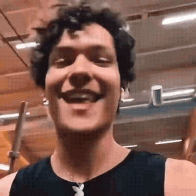 Man With Curly Hair Smiling In Gym Wearing Playboy Necklace GIF