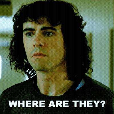 Man With Curly Hair Standing In Front Of Where Are They Sign GIF