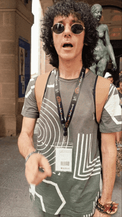 Man With Curly Hair Sunglasses And 'A Few Words' Lanyard GIF