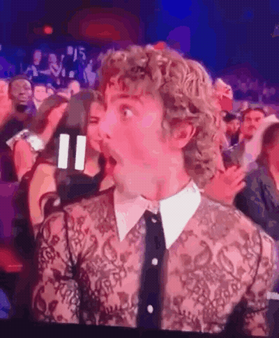 Man With Curly Hair Surprised In Crowd GIF