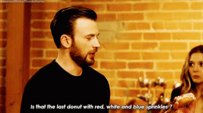 Man With Donut Talking To Woman In Front Of Brick Wall GIF