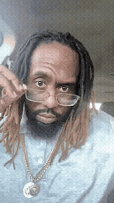 Man With Dreadlocks And Glasses Wearing Necklace And Blue Shirt GIF