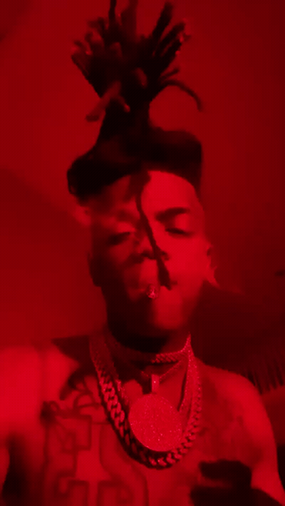 Man With Dreadlocks And Necklace Smoking In Red Room GIF