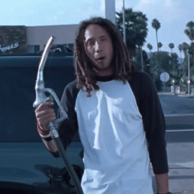 Man With Dreadlocks Holding Gas Pump in Front of Focus Building