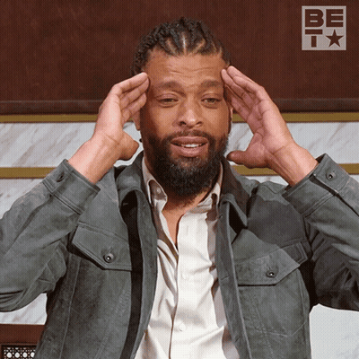 Man With Dreadlocks Holding Head In Front Of Be It Sign GIF