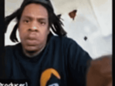 Man With Dreadlocks In Black Shirt With Yellow Arrow GIF