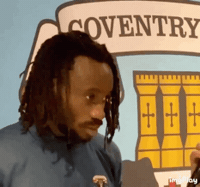 Man With Dreadlocks In Front Of Coventry Sign GIF