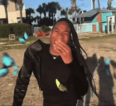 Man With Dreadlocks Laughing In Front Of Blue Building GIF