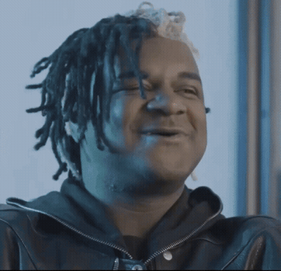 Man With Dreadlocks On Couch Holding Money Bag GIF