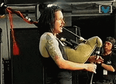 Man With Dreadlocks Playing Bagpipe On Stage GIF