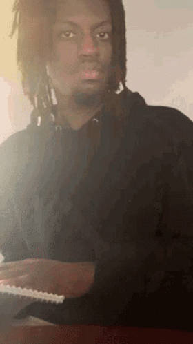 Man With Dreadlocks Sitting At Table With Notebook GIF