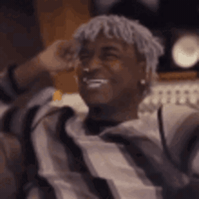 Man With Dreadlocks Sitting On Couch Hands Behind Head GIF