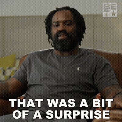 Man With Dreadlocks Sitting On Couch Saying That Was A Bit Of A Surprise GIF