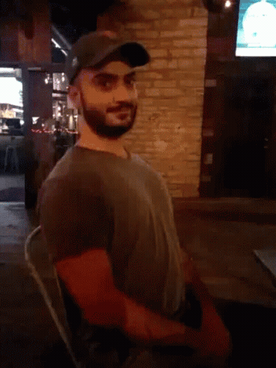 Man With Ear Piercing Looking At Camera In Dark Room GIF