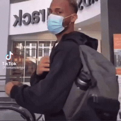 Man With Face Mask And Backpack In Front Of Building Saying Black GIF