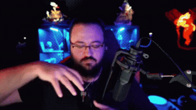 Man With Glasses And Beard At Microphone In Dark Room GIF