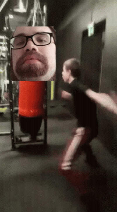 Man With Glasses And Beard In Front Of Red Bag GIF
