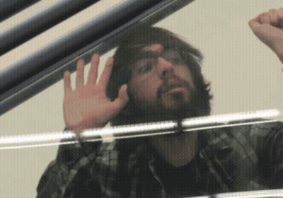 Man With Glasses And Beard Looking Through Glass Door GIF