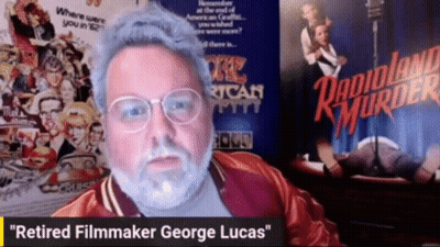 Man With Glasses And Beard Sitting In Front Of Danioland Murder Poster GIF