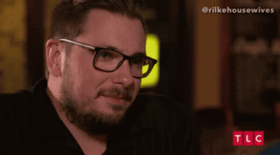 Man With Glasses And Beard Sitting In Front Of TLC Screen GIF
