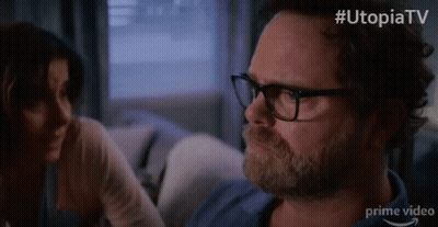 Man With Glasses And Beard Sitting On Couch With Woman Behind GIF