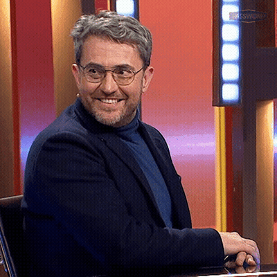 Man With Glasses And Beard Smiling In Front Of Das Samstags Sign GIF