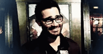 Man With Glasses And Beard Smiling In Front Of Door GIF