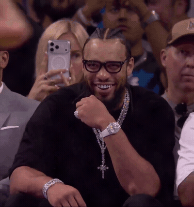 Man With Glasses And Cross Necklace Smiling In Stands GIF