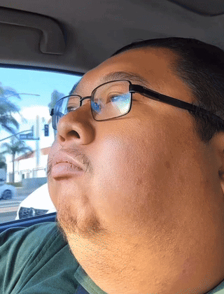 Man With Glasses And Green Shirt Looks Out Window GIF