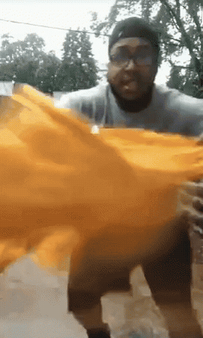 Man With Glasses And Hat Holding Orange Cloth GIF