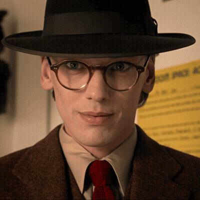 Man With Glasses And Hat In Front Of Yellow Sign Saying A GIF