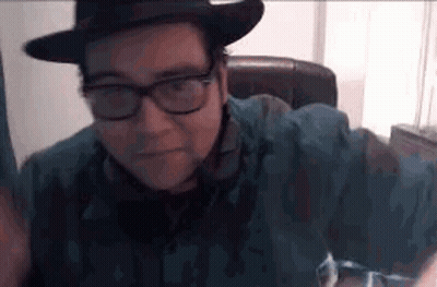 Man With Glasses And Hat Sitting In Chair GIF