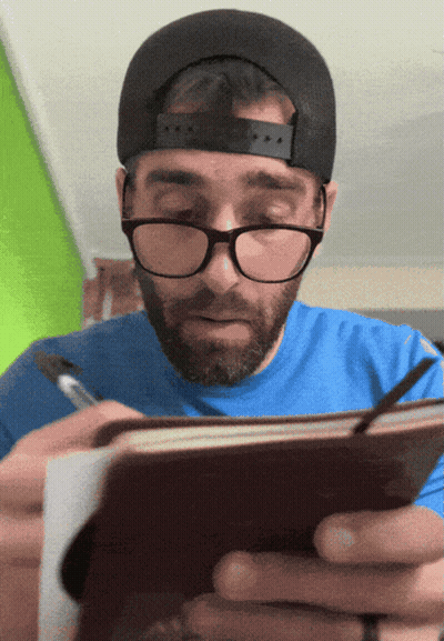 Man With Glasses And Hat Writing In Notebook GIF