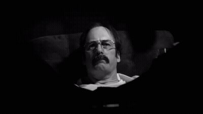 Man With Glasses And Mustache Laying In Chair In Dark Room GIF