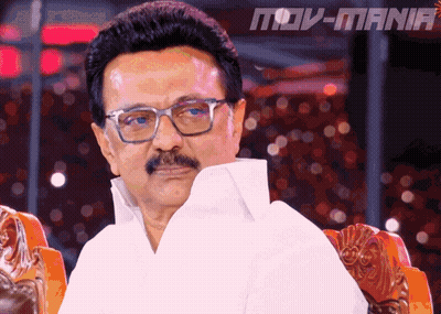 Man With Glasses And Mustache Sitting At Movi-Mania Sign GIF