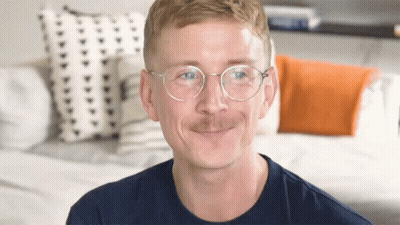 Man With Glasses And Mustache Smiling On Couch GIF
