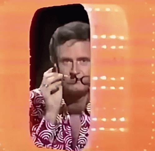 Man With Glasses And Purple Shirt Smoking By Window GIF