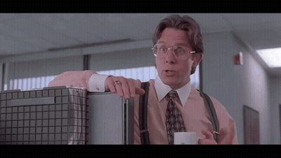 Man With Glasses And Suspenders Leaning On Cubicle With Coffee GIF