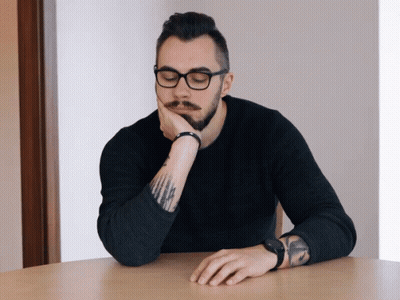 Man With Glasses and Tattoo Resting Hand on Chin