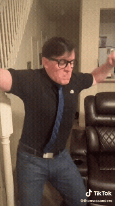 Man With Glasses And Tie Dancing In Front Of Couch And Stairs GIF