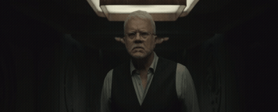 Man With Glasses And Vest Standing In Dark Room GIF