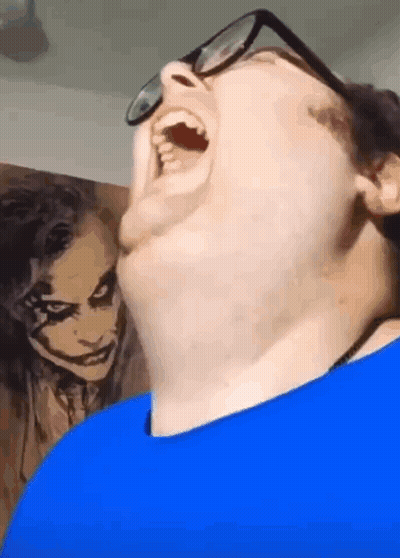 Man With Glasses Funny Face In Front Of Joker Painting GIF