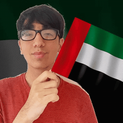 Man With Glasses Holding Flag In Front Of Green And White Flag GIF
