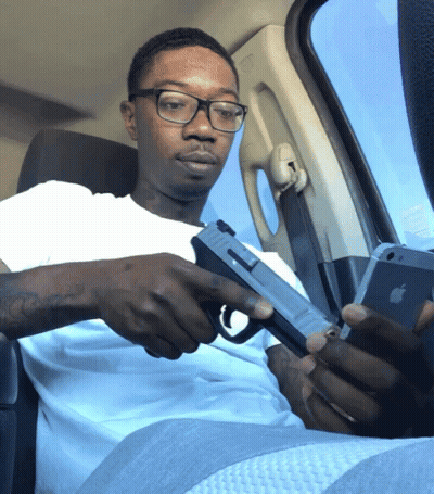 Man With Glasses Holding Gun Looking At Phone GIF