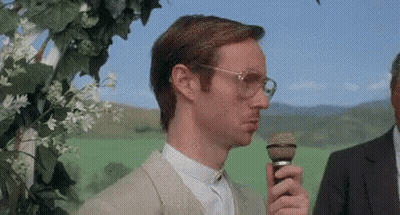 Man With Glasses Holding Microphone In Green Field GIF