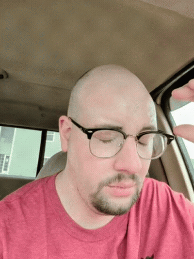 Man With Glasses In Red Shirt Eyes Closed In Car GIF