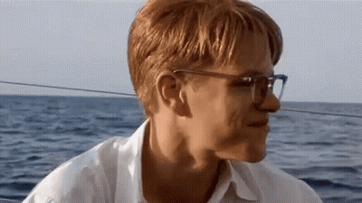 Man With Glasses Sitting On Boat Looking At Ocean GIF