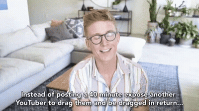 Man With Glasses Smiling In Front Of Couch And Coffee Table GIF